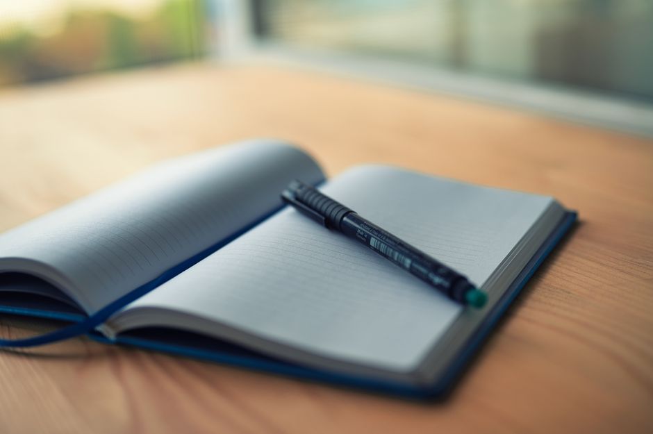 Carnet ouvert avec un stylo posé sur un bureau en bois