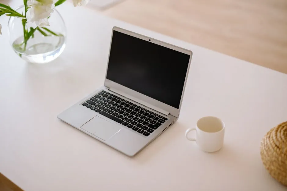 Ordinateur portable ouvert sur une table blanche avec une tasse de café