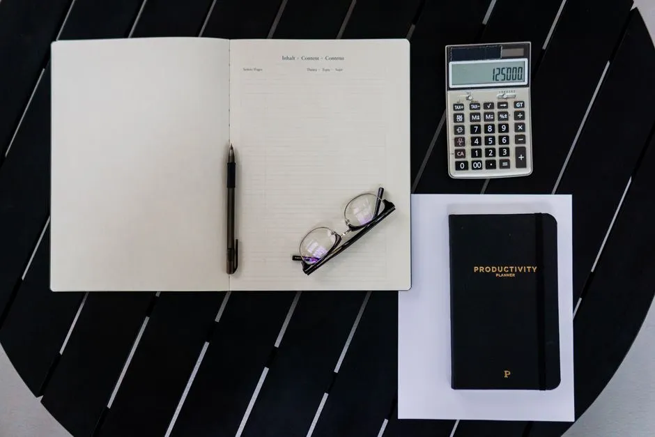Carnet, calculatrice et stylo sur un bureau, vus de dessus