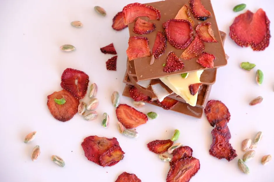 Tablettes de chocolat au lait garnies de fraises séchées, entourées de pistaches
