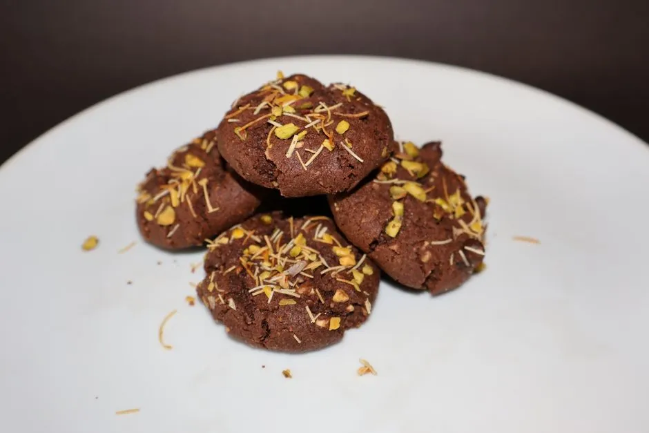 Cookies au chocolat garnis de pistache et de kadaïf, dans une assiette blanche