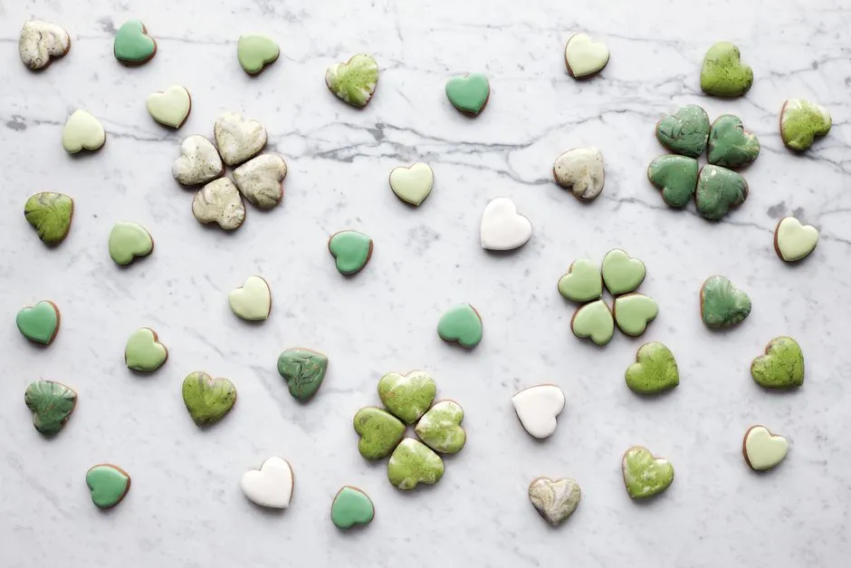 Assortiment de cookies faits maison, aux couleurs et motifs variés, disposés sur une table en marbre