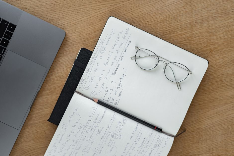 Carnet ouvert et stylo sur un bureau en bois, vus de dessus