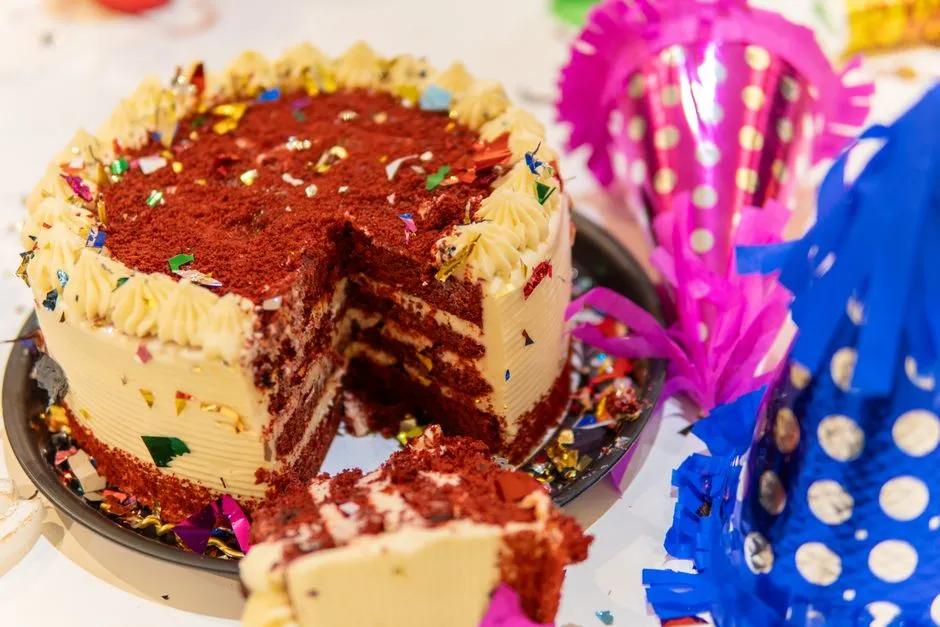 Gâteau red velvet entamé, entouré de chapeaux de fête et de confettis