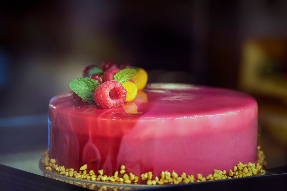 Entremets au glaçage miroir framboise décoré de fruits rouges