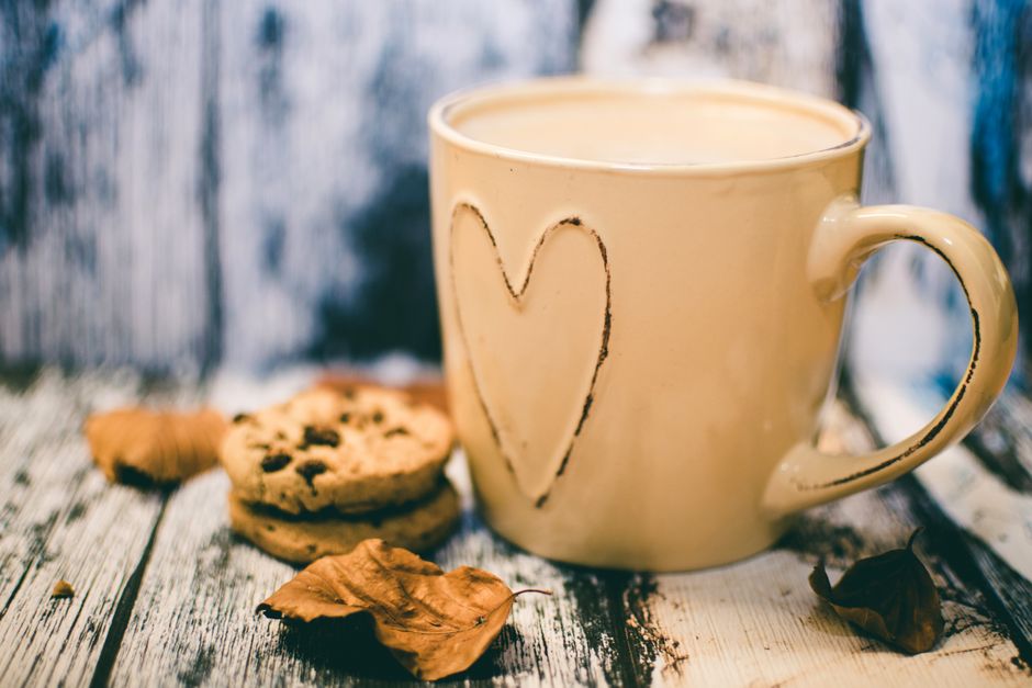 Tasse de café posée à côté d'un cookie au chocolat sur une table en bois