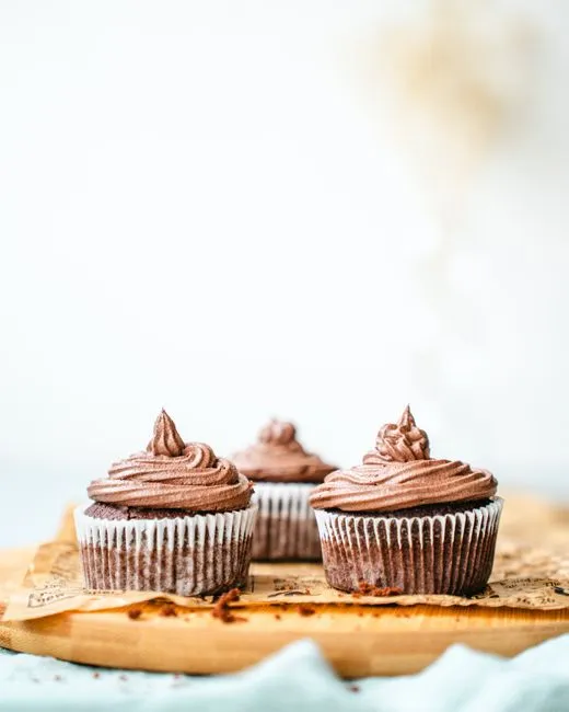 Trois cupcakes au chocolat posés sur une planche en bois